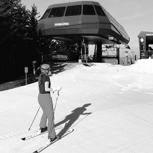 Jia Ivey on skis at the top of a lift, in black and white